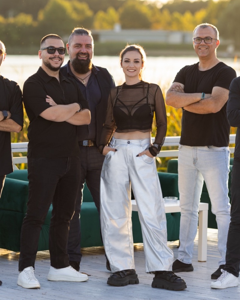 Membri ai trupei, în negru, pe o terasă la apus