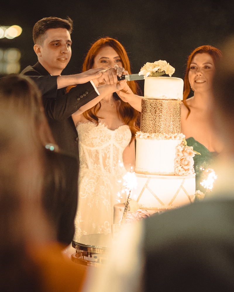 Mirii taie tortul afară, seara, cu artificii de tort aprinse lângă etajele tortului