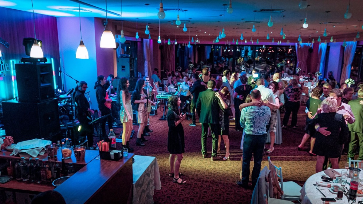 Trupa cântând într-o sală de evenimente, cu invitații dansând pe ring