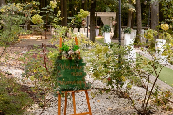 Panoul de bun venit, printre tufișurile din grădina localului