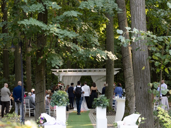 Cununia religioasă în desfășurare, în pădure, cu invitații de o parte și de alta a aleii