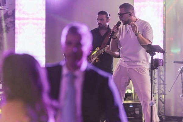 Matei cântând lângă chitarist, cu un invitat dansând în prim-plan