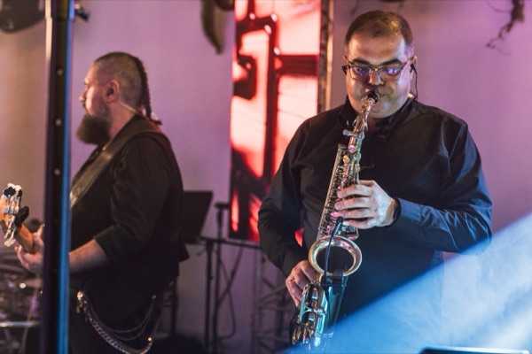 Saxofonistul și basistul pe scenă, în lumină roz