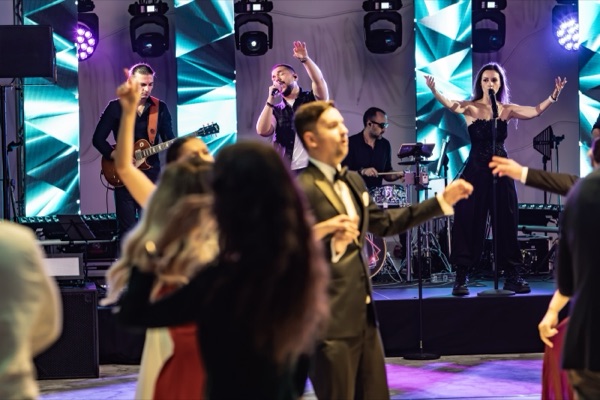 Invitați dansând în fața scenei, cu soliștii și stâlpii LED în fundal
