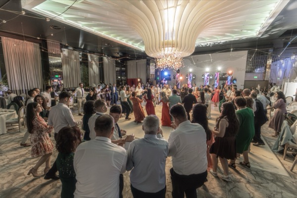 Horă mare sub candelabrul salonului, cu Cătălin cântând în mijlocul ei
