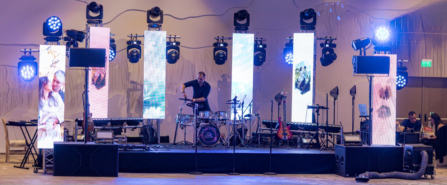 Scena The Fun Station Band montată la Lacul Roșu: șase stâlpi LED cu lumini pe capete, tobele în centru și boxele pe laterale