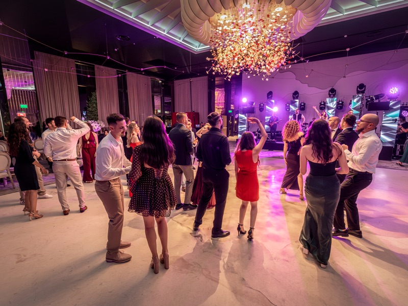 Invitați dansând în sala de evenimente, sub candelabru